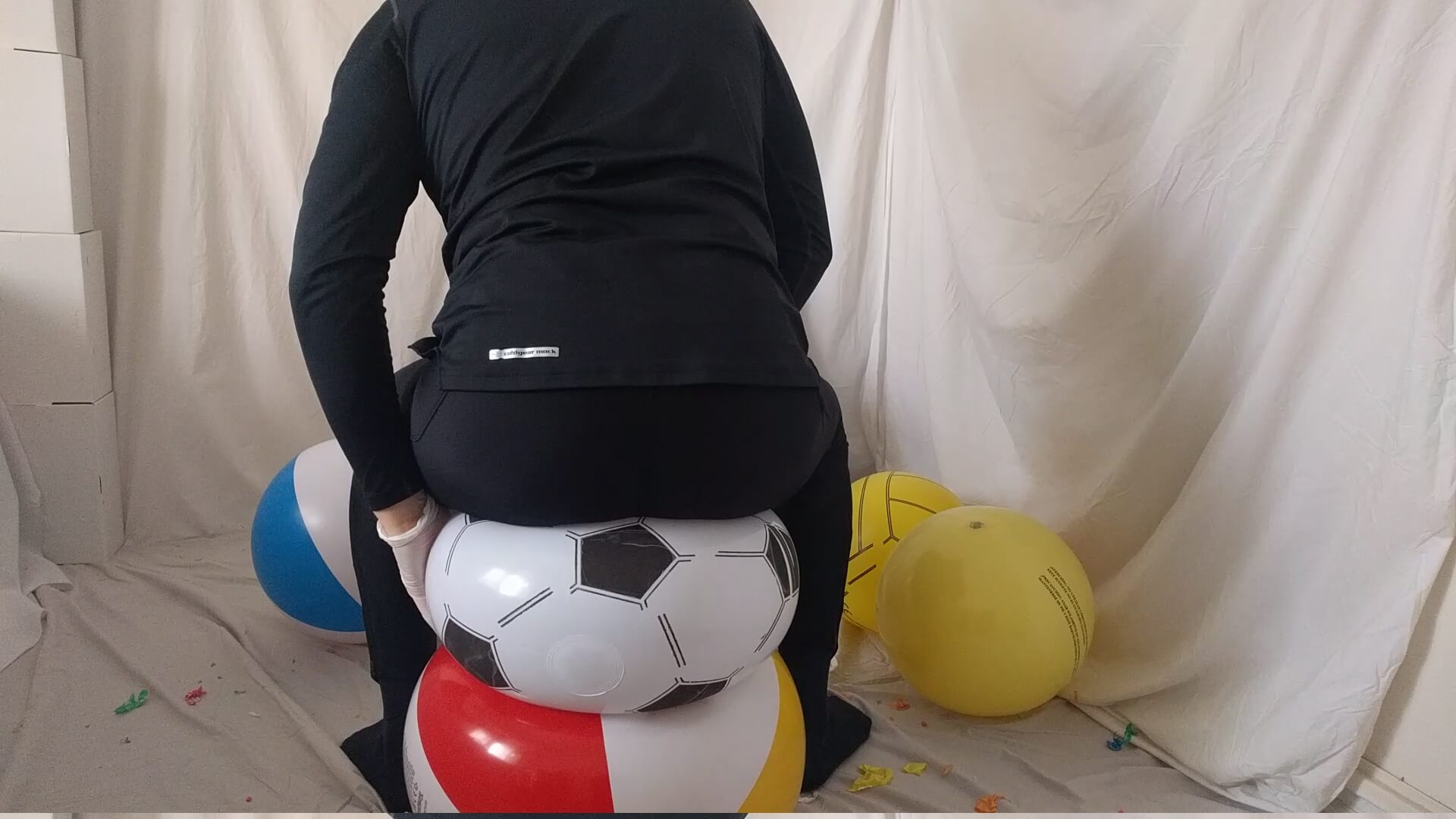 Man sit popping two beach balls together on the floor in tights | reventemos.com