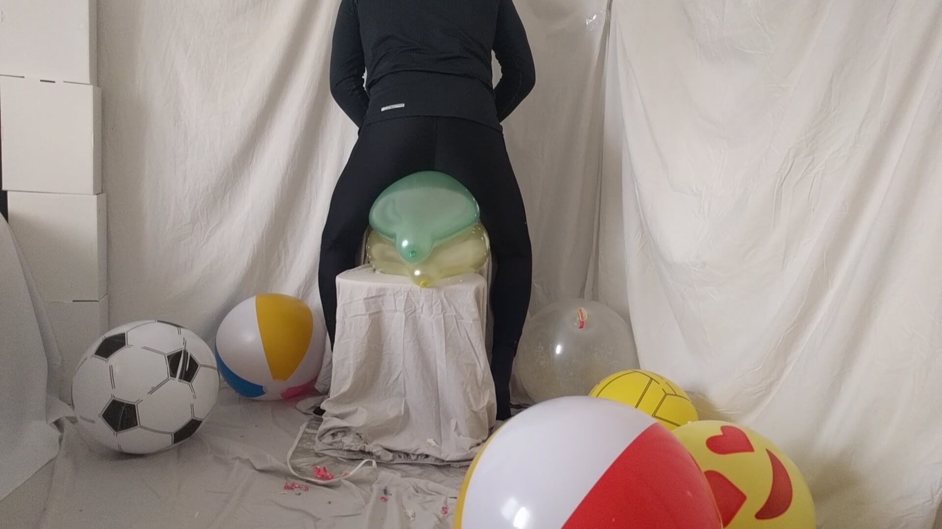 Riding 2 balloons at the same time on a chair in leggings