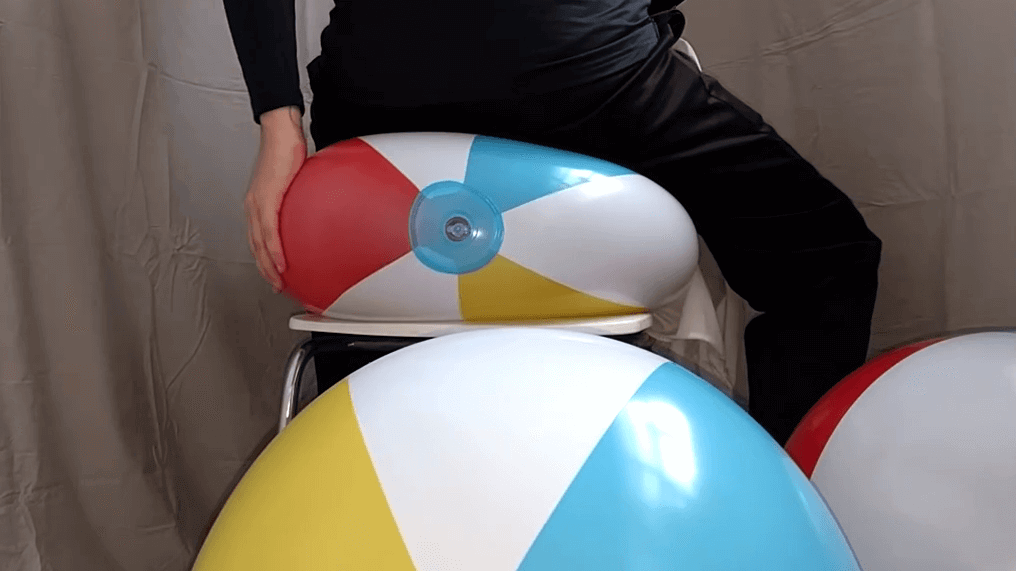 Sit popping a 41-inch beachball on a chair in joggings