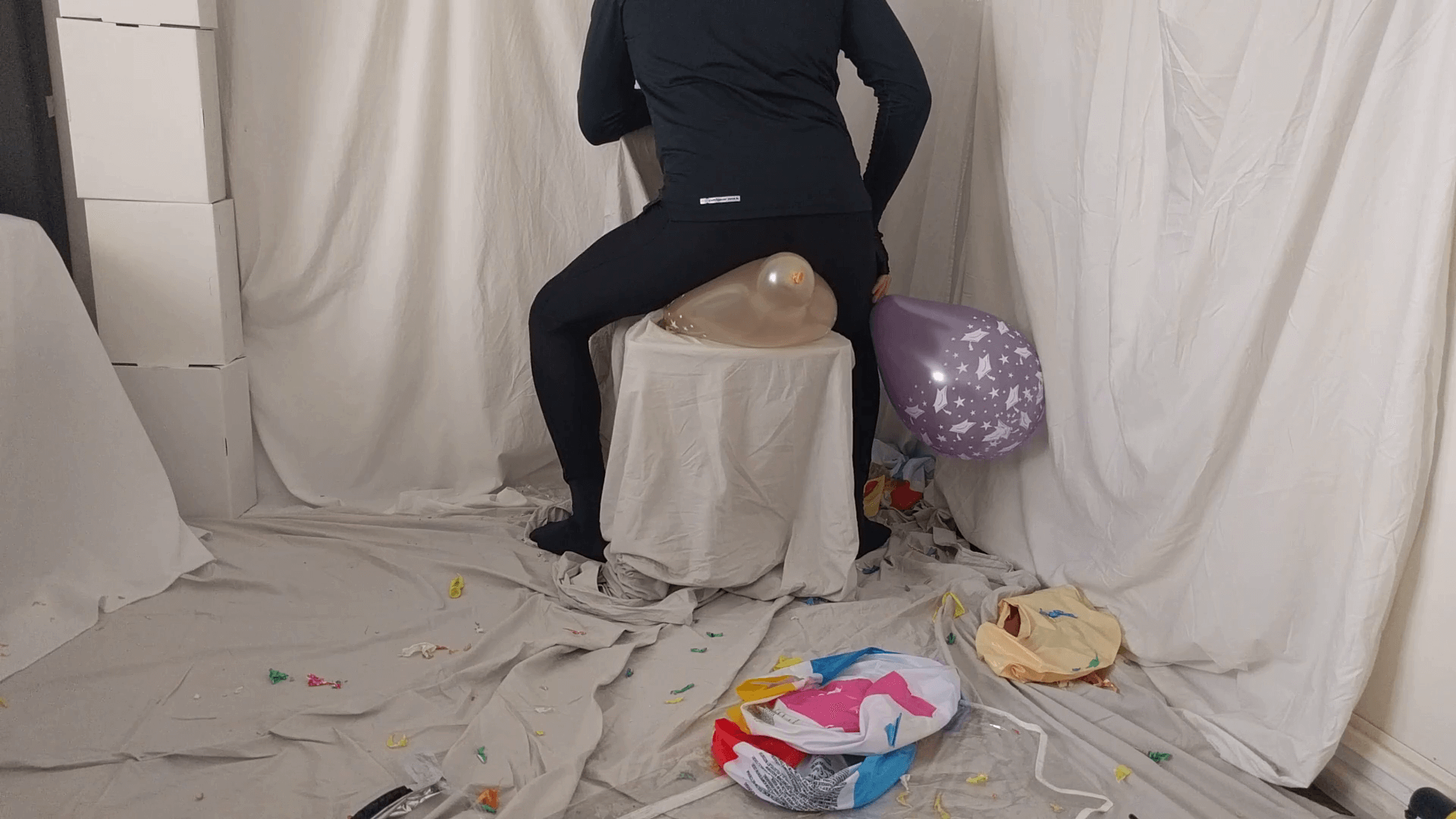 Sit popping some small balloons in leggings on a chair