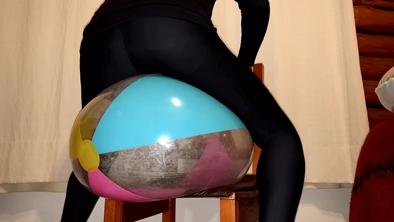 Sit popping a paradise beach ball in the dark in leggings